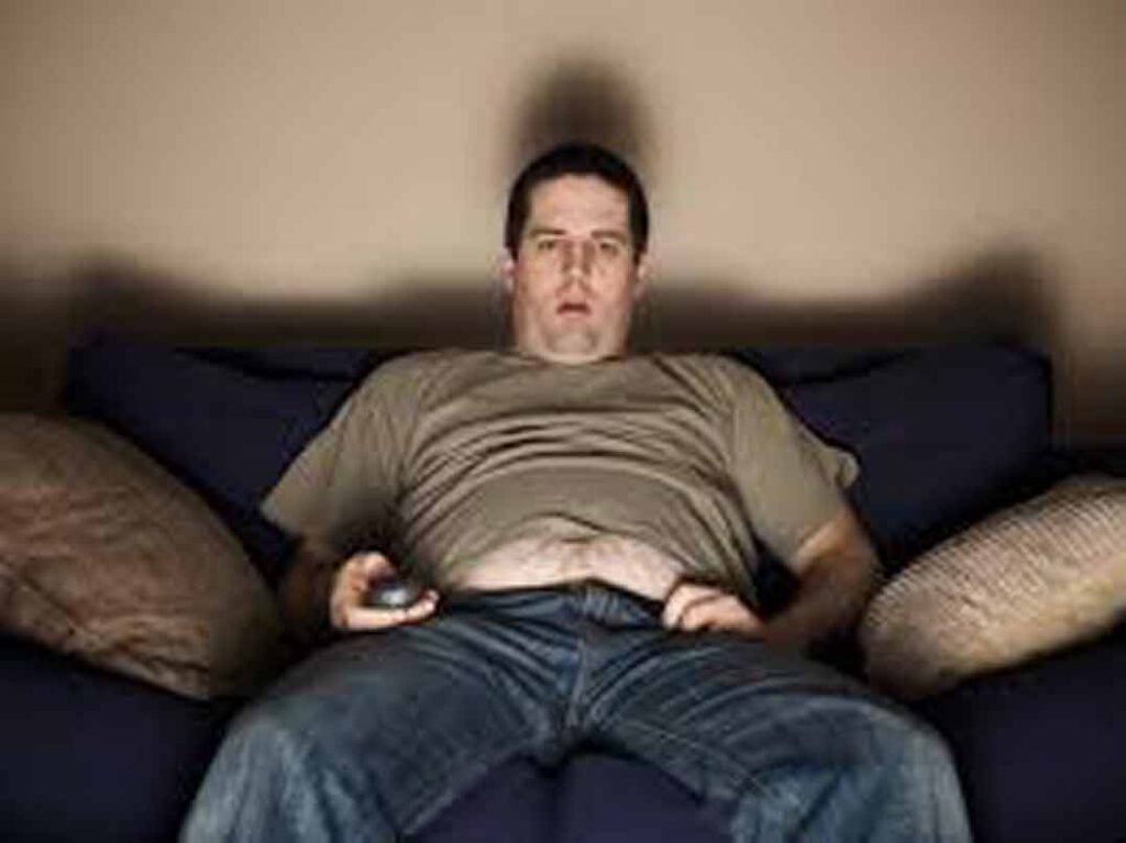 Gordo viendo la tele, con mando en la mano y cara de tonto