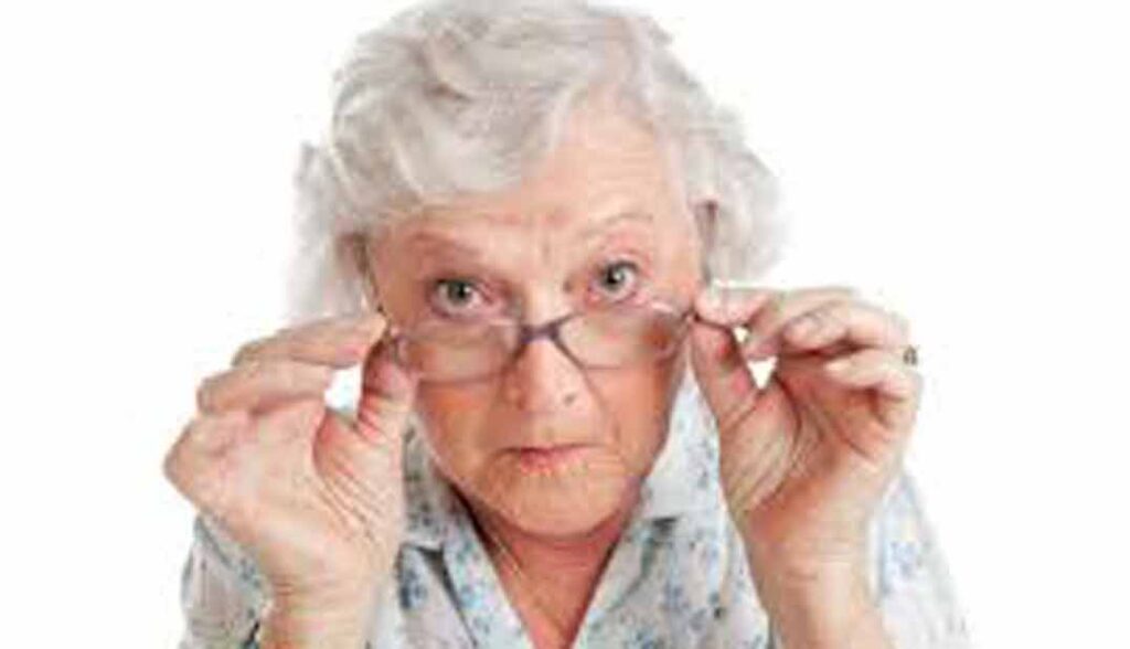 abuela tocándose con ambas manos las gafas observando a la cámara actitud crítica