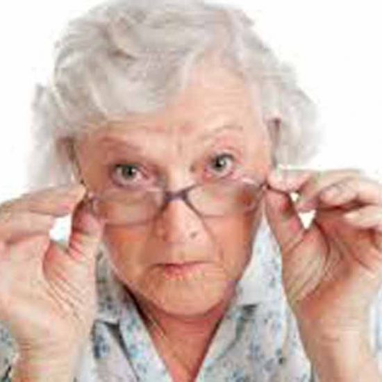 abuela tocándose con ambas manos las gafas observando a la cámara actitud crítica
